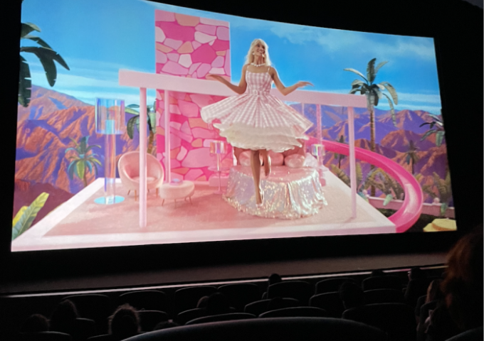 Bild von der Kinoleinwand mit Barbie die von ihrem Dreamhouse herunter schwebt